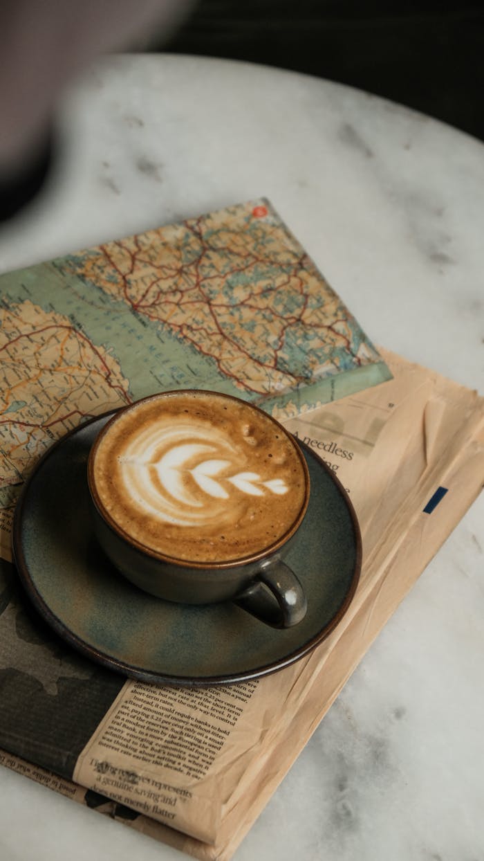services-img Artistic cappuccino on newspapers and a map, perfect for travel inspiration.